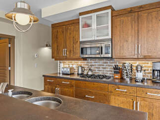This kitchen boasts beautiful rustic wooden cabinetry complemented by a modern stainless steel microwave and gas stovetop.
