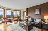 Experience breathtaking mountain views from this stunning living room, featuring a cozy leather sofa and two accent chairs perfect for relaxing.