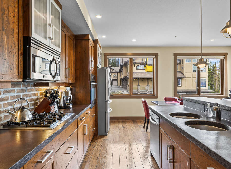 Experience luxury mountain living in this stunning kitchen featuring rich wood cabinetry and sleek stainless steel appliances.
