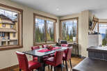 Experience breathtaking mountain views from this elegant dining area, featuring a spacious dark wood table surrounded by plush red chairs.