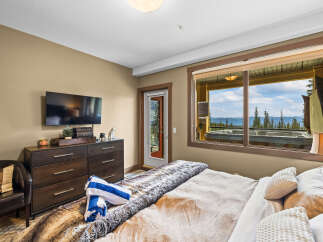 Experience ultimate relaxation in this luxurious bedroom, featuring a plush fur throw and a private balcony with a hot tub overlooking a stunning mountain vista.