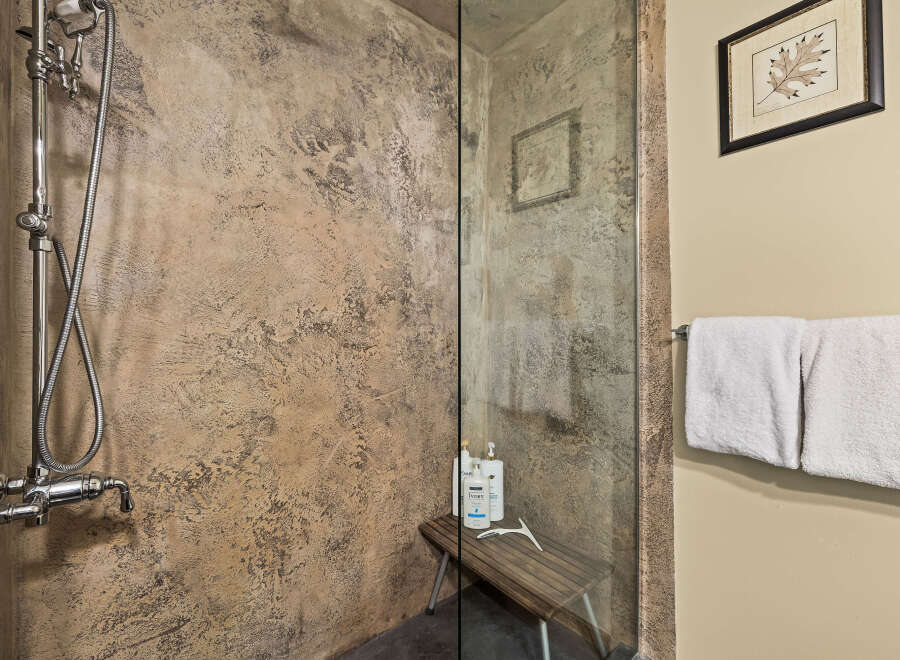 Experience a spa-like retreat in this modern bathroom featuring a textured stone shower enclosure and a sleek chrome shower system.