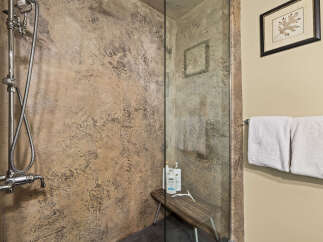 Experience a spa-like retreat in this modern bathroom featuring a textured stone shower enclosure and a sleek chrome shower system.
