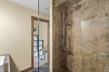 Experience luxury in this modern bathroom featuring a spacious walk-in shower with a rainfall showerhead and a sleek, textured stone finish.