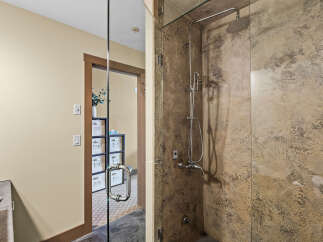 Experience luxury in this modern bathroom featuring a spacious walk-in shower with a rainfall showerhead and a sleek, textured stone finish.