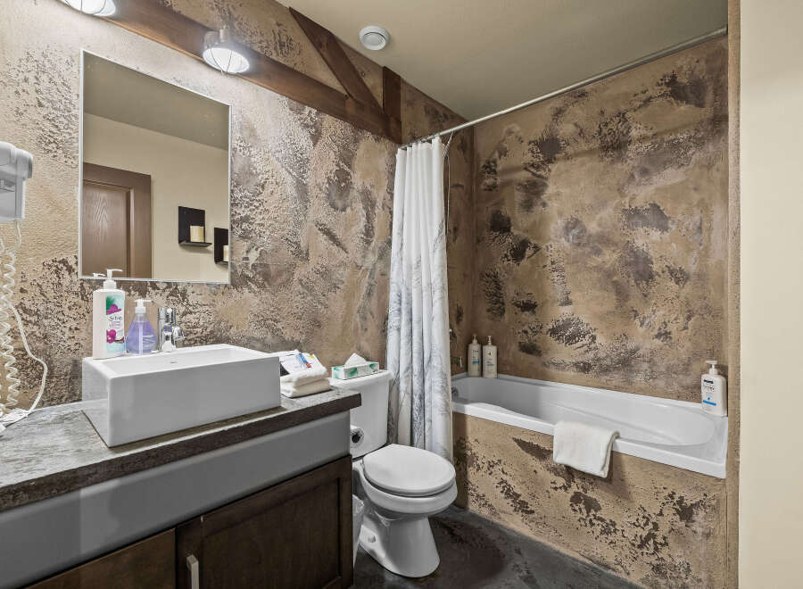 This rustic bathroom features a textured, earthy-toned wall that adds a unique charm.