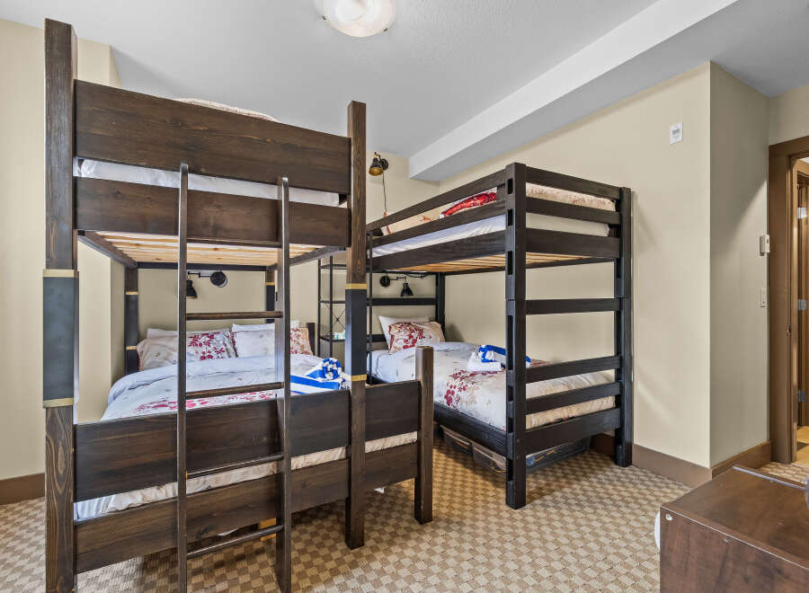 This spacious bedroom is perfect for families or groups, featuring two sets of dark wood bunk beds.