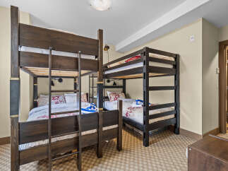 This spacious bedroom is perfect for families or groups, featuring two sets of dark wood bunk beds.