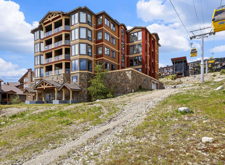 Experience luxury mountain living in this stunning condo complex, featuring modern architecture with stone and wood accents.