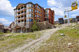 Experience luxury mountain living in this stunning condo complex, featuring modern architecture with stone and wood accents.