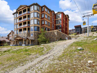 Experience luxury mountain living in this stunning condo complex, featuring modern architecture with stone and wood accents.