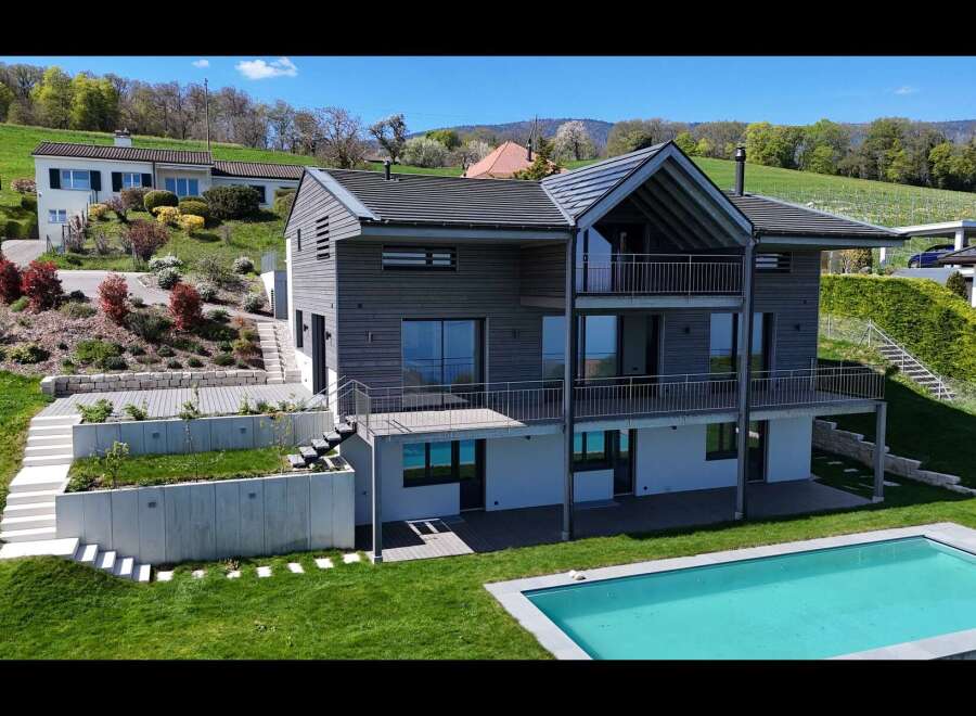 Experience modern luxury in this stunning multi-level home featuring sleek grey siding and expansive balconies perfect for enjoying the scenic hillside views.