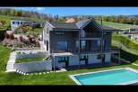 Experience modern luxury in this stunning multi-level home featuring sleek grey siding and expansive balconies perfect for enjoying the scenic hillside views.