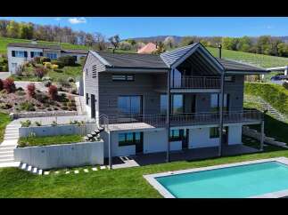 Experience modern luxury in this stunning multi-level home featuring sleek grey siding and expansive balconies perfect for enjoying the scenic hillside views.
