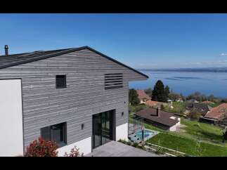 Experience modern living with this stunning home featuring sleek horizontal wood siding and expansive glass doors.