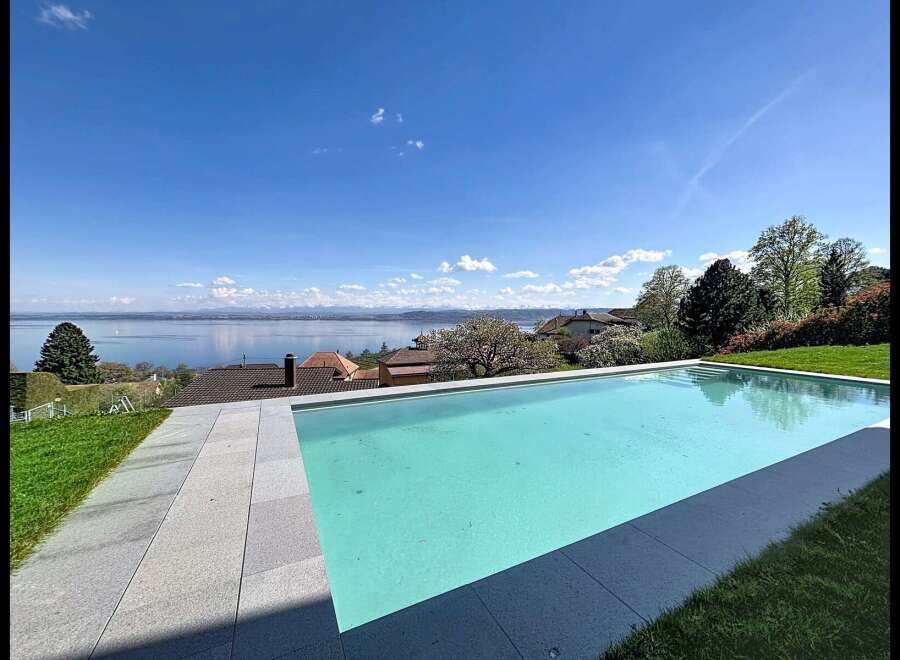 Experience luxury living with this stunning infinity pool offering breathtaking panoramic views of a serene lake and distant mountains.