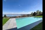 Experience luxury living with this stunning infinity pool offering breathtaking panoramic views of a serene lake and distant mountains.