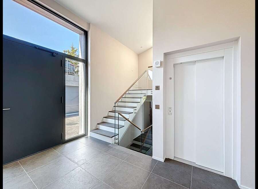 Step into modern luxury with this stunning entryway featuring a sleek dark gray door and expansive windows that flood the space with natural light.