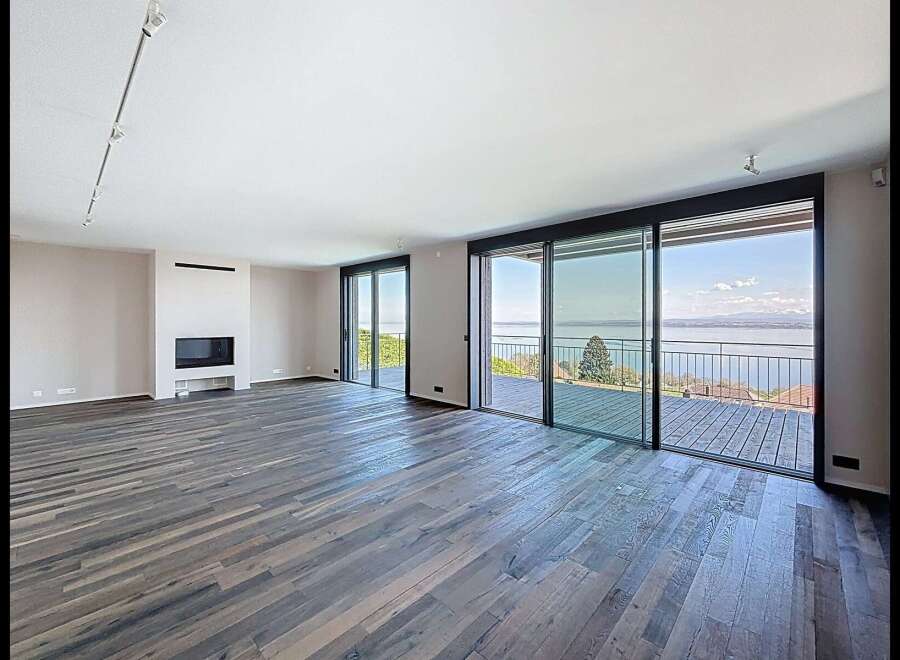 Experience breathtaking lake views from this spacious living area, featuring a modern fireplace and expansive sliding glass doors that open onto a private deck.