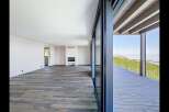 Experience modern living in this spacious open-plan room featuring a sleek fireplace and expansive glass doors.