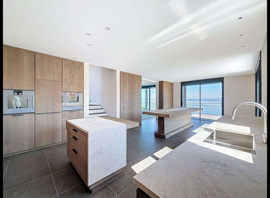 Experience modern luxury in this spacious open-plan kitchen featuring sleek wooden cabinetry and integrated appliances.