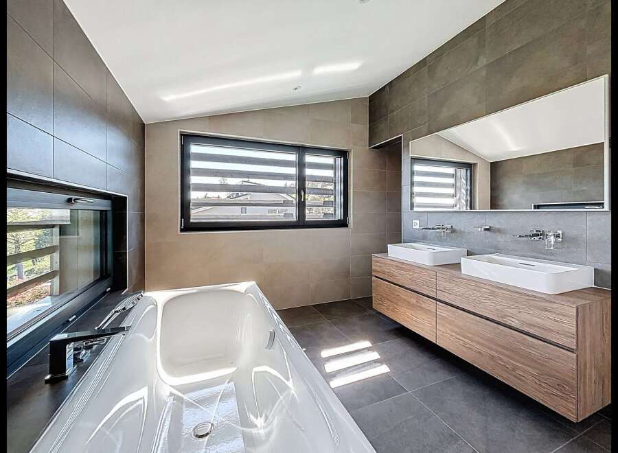 Experience modern luxury in this stunning bathroom featuring a deep soaking tub and a sleek double vanity with vessel sinks.