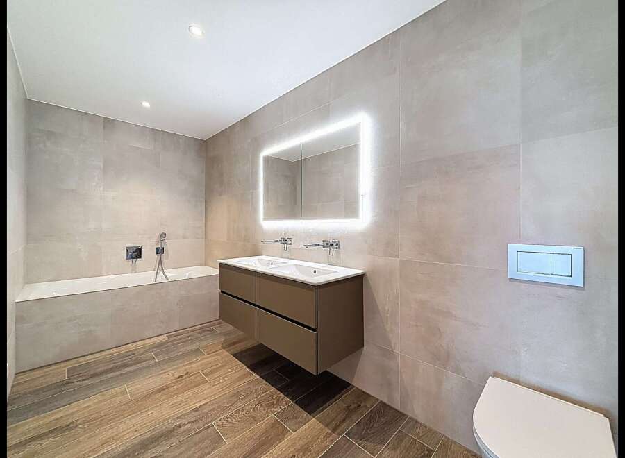 Experience modern luxury in this stunning bathroom featuring a sleek double vanity with integrated lighting and a spacious bathtub.