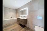 Experience modern luxury in this stunning bathroom featuring a sleek double vanity with integrated lighting and a spacious bathtub.