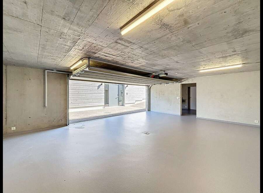 Discover this spacious and modern garage, featuring a durable concrete ceiling and walls, complemented by a sleek, light-colored epoxy floor.