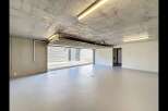Discover this spacious and modern garage, featuring a durable concrete ceiling and walls, complemented by a sleek, light-colored epoxy floor.
