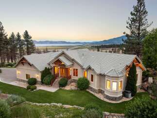 Experience luxury living in this stunning custom-built home, boasting panoramic views of the serene lake and majestic mountains.
