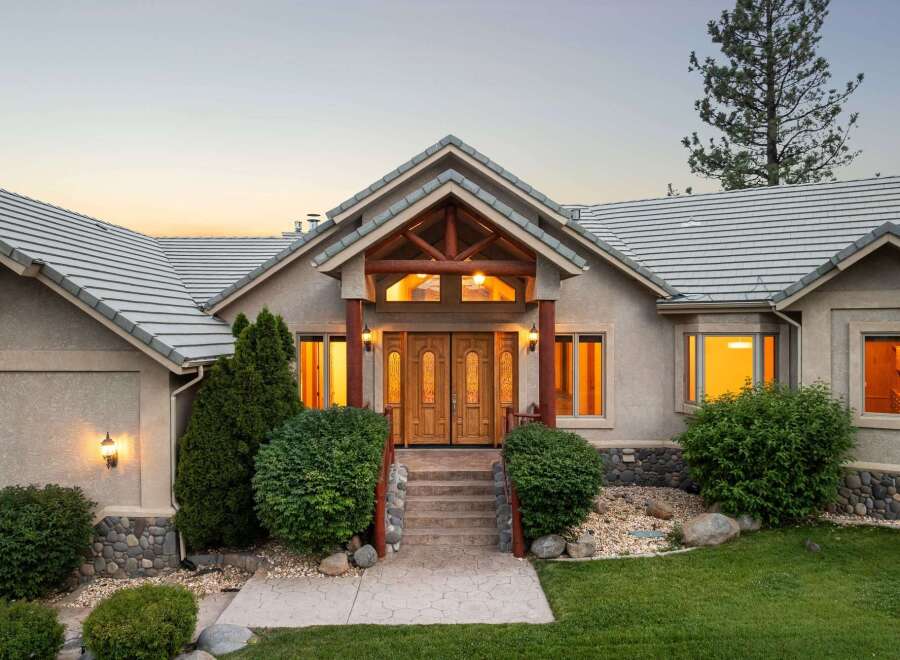 Experience luxury living in this stunning home featuring a grand entrance with double wooden doors and a covered porch.
