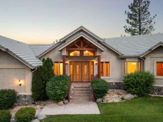 Experience luxury living in this stunning home featuring a grand entrance with double wooden doors and a covered porch.