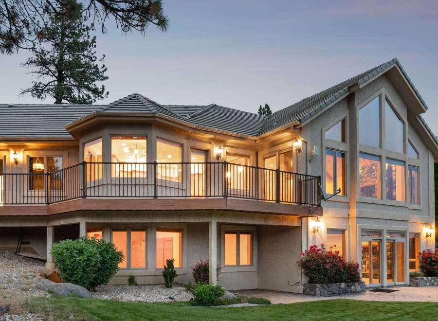 This stunning home features a multi-level deck with black railings, perfect for enjoying the scenic views.