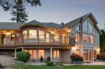 This stunning home features a multi-level deck with black railings, perfect for enjoying the scenic views.