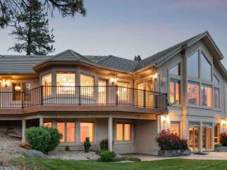 This stunning home features a multi-level deck with black railings, perfect for enjoying the scenic views.