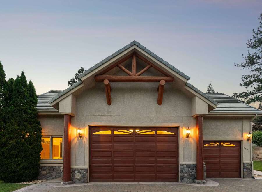 Experience rustic charm with this stunning home featuring a prominent wooden truss gable above a rich brown garage door.