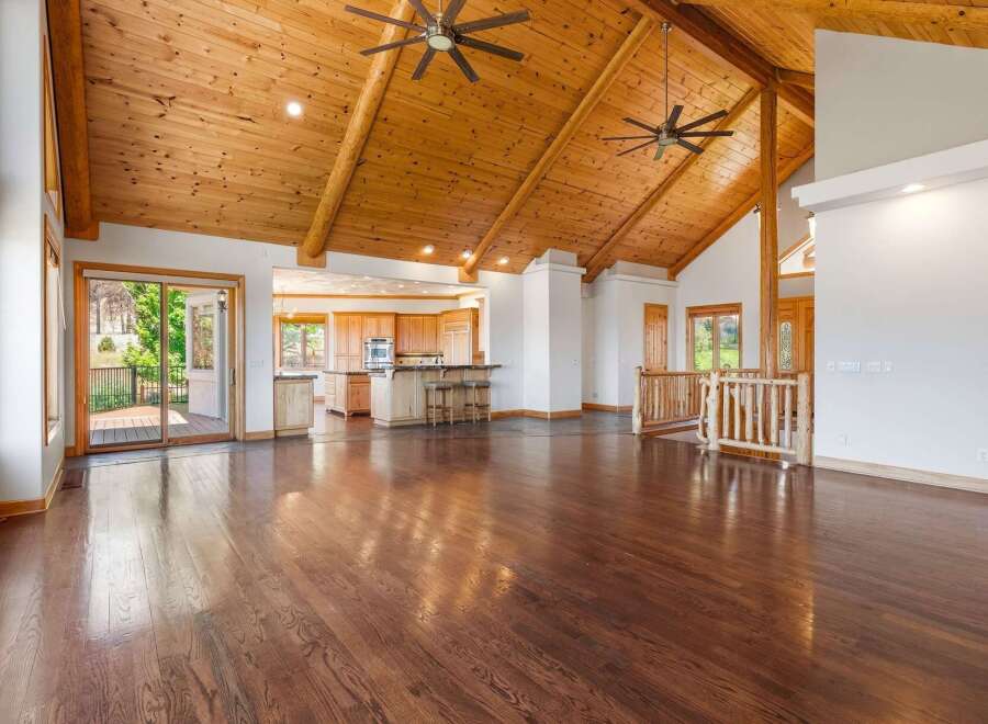 Experience luxurious living in this spacious open-concept home featuring a stunning vaulted wood-beam ceiling and gleaming hardwood floors.