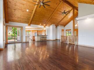 Experience luxurious living in this spacious open-concept home featuring a stunning vaulted wood-beam ceiling and gleaming hardwood floors.