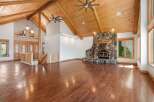 Experience rustic charm in this spacious living area featuring a grand stone fireplace and soaring vaulted ceilings with exposed wooden beams.