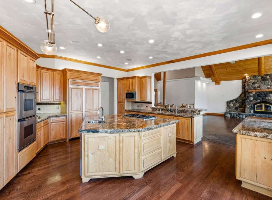 Experience luxury in this expansive kitchen featuring custom light wood cabinetry and granite countertops.