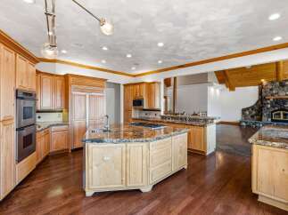 Experience luxury in this expansive kitchen featuring custom light wood cabinetry and granite countertops.