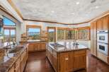 Experience breathtaking mountain views from this stunning kitchen, featuring a large granite island with a gas stovetop and a double sink.