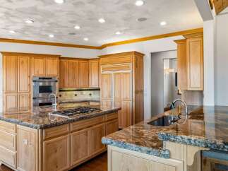 Experience luxury in this spacious kitchen featuring custom wood cabinetry and stunning granite countertops.