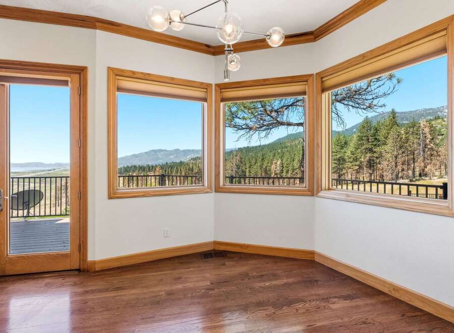 Experience breathtaking panoramic views from this stunning room, featuring expansive windows that showcase a lush forest and distant mountains.