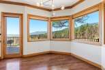 Experience breathtaking panoramic views from this stunning room, featuring expansive windows that showcase a lush forest and distant mountains.