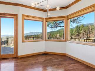 Experience breathtaking panoramic views from this stunning room, featuring expansive windows that showcase a lush forest and distant mountains.