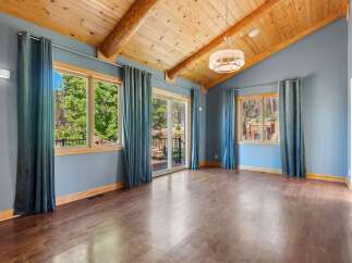 Experience breathtaking natural beauty from this stunning living space, featuring a vaulted wood-beamed ceiling and expansive windows that flood the room with natural light.