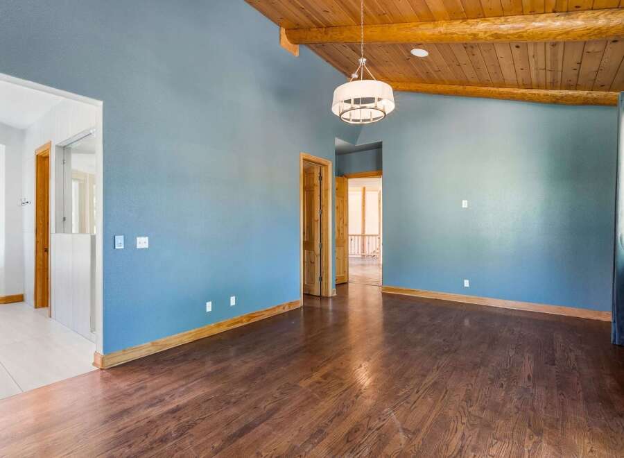 Experience the warmth of this inviting living space, featuring a stunning vaulted wood-beamed ceiling and a modern drum pendant light.