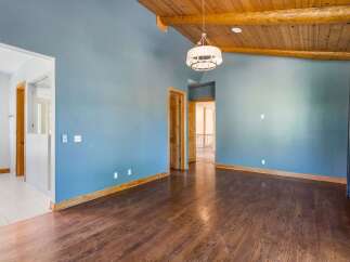 Experience the warmth of this inviting living space, featuring a stunning vaulted wood-beamed ceiling and a modern drum pendant light.